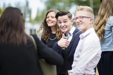 Auf den Bild ist im Vordergrund ein junger Student der sächsischen Steuer- und Finanzverwaltung abgebildet welcher seinen Daumen nach oben streckt und damit in Richtung der Kamera sein Glück und seine Freude signalisiert. Das Bild wurde im Rahmen der zent